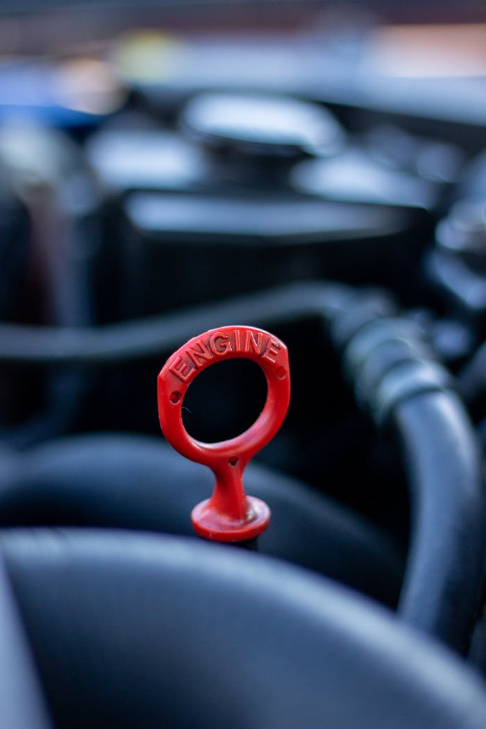 Mastering the First Impression: Your intriguing post title goes here Detailed view of a red engine dipstick in an automobile, emphasizing selective focus and automotive mechanics.